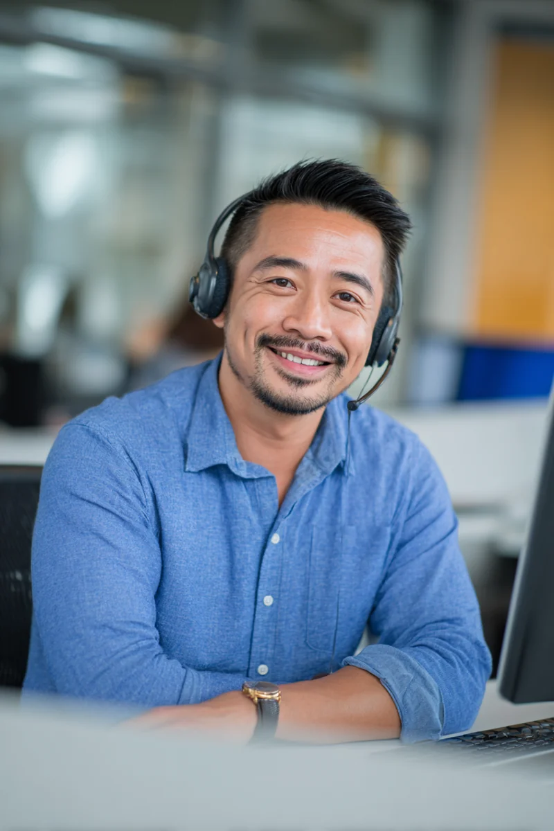 Filipino American customer support lead with a wireless headset at a clean modern desk